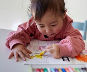 little girl coloring in a coloring book by Aflo Images via Canva